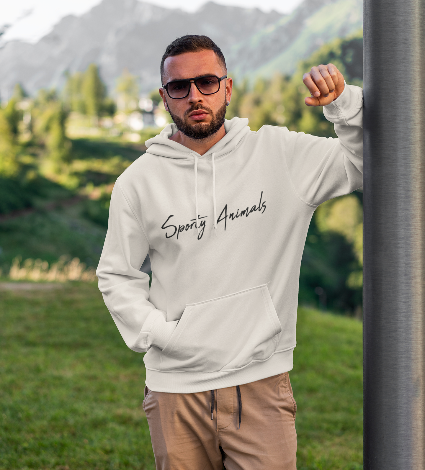 Ein Mann trägt einen Hoodie in der Farbe hell beige. Auf dem Hoodie ist vorne der Schriftzug "Sporty Animals"